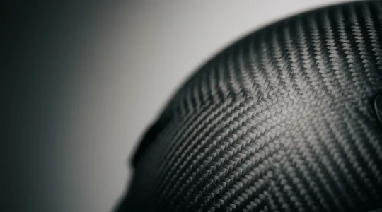 Premium-Carbonhelm für Motorräder mit sichtbarer Kohlefaserstruktur in professioneller Nahaufnahme