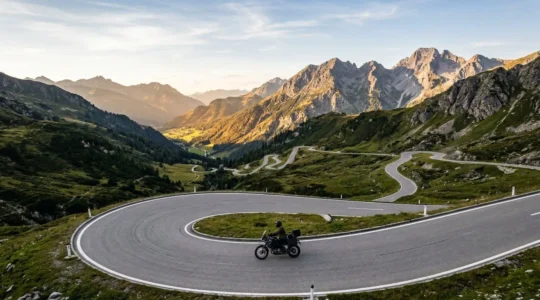 Motorradfahrer navigiert durch enge Alpenpässe mit dramatischen Serpentinen vor majestätischen Berggipfeln