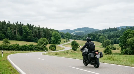Motorradfahrer mit Navigationssystem auf kurvenreicher deutscher Landstraße