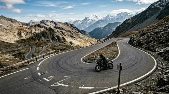 Motorradfahrer navigiert durch spektakuläre Serpentinen auf einem hochalpinen Pass mit dramatischer Bergkulisse