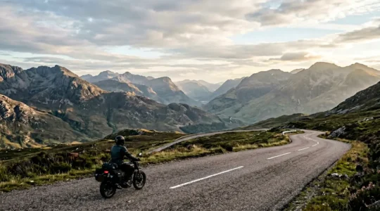 Motorradfahrer auf kurviger Bergstraße vor weitem Horizont