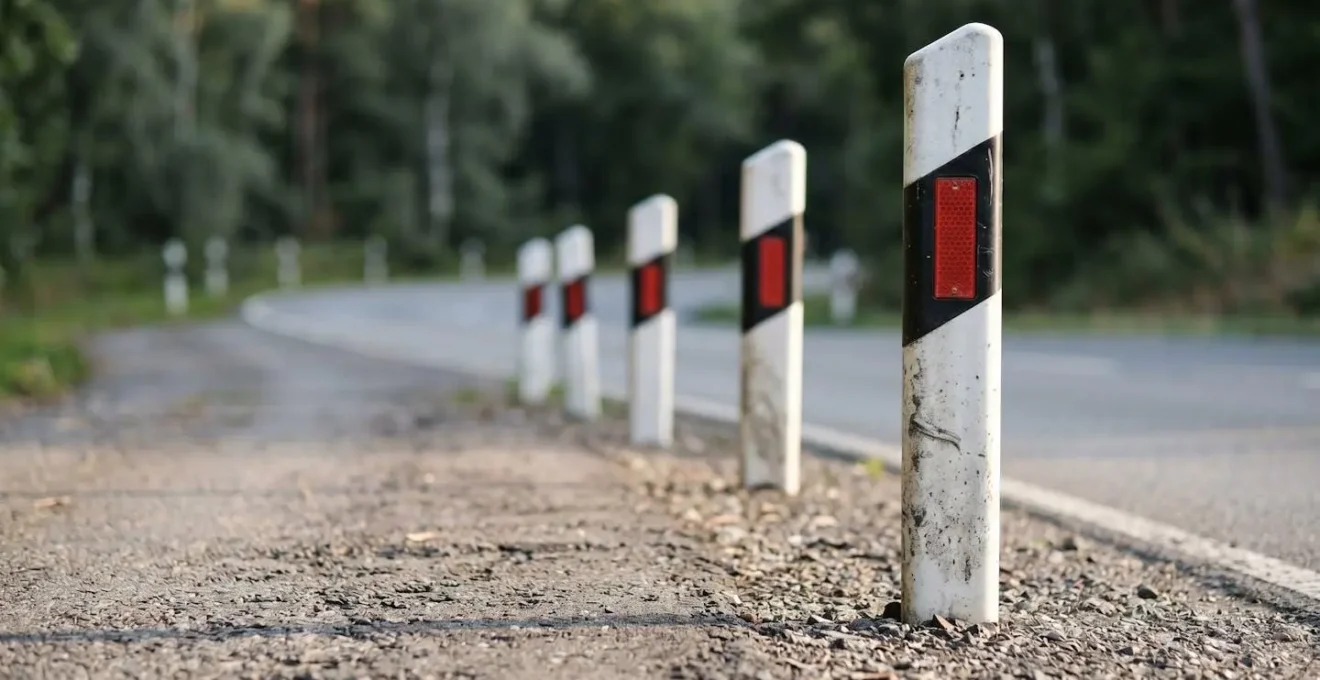 Nahaufnahme schwarz-weisser Leitpfosten entlang kurviger Landstrasse zur Kurvenradiusbestimmung