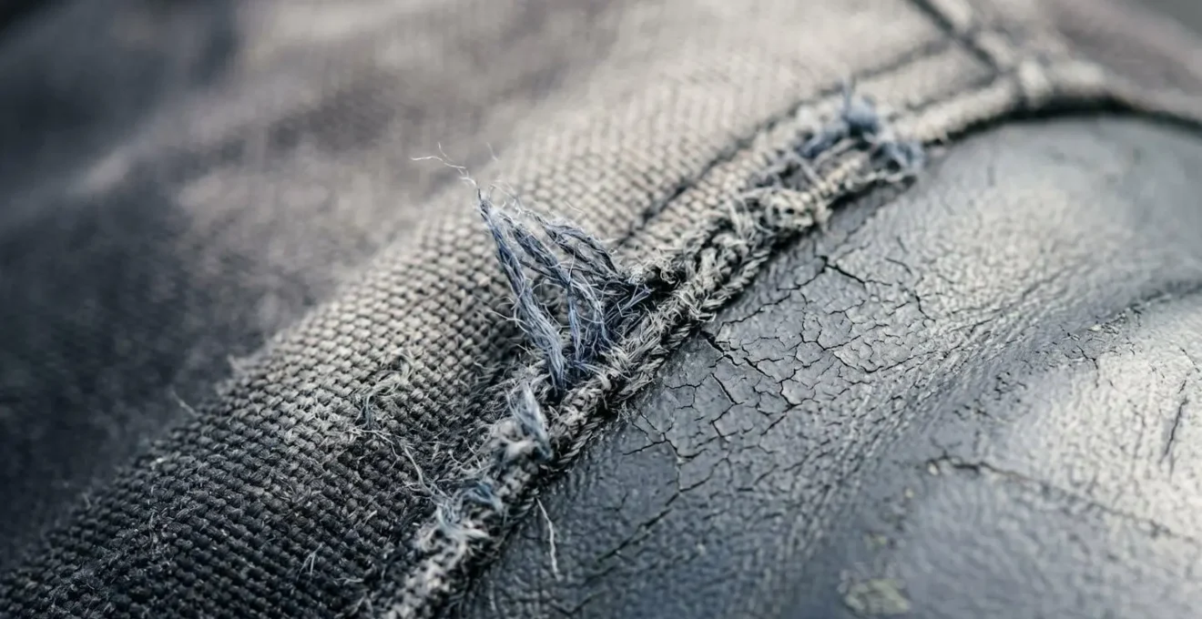 Detailaufnahme einer gealterten Motorradjacke mit sichtbaren Abnutzungsspuren an Nähten und Material